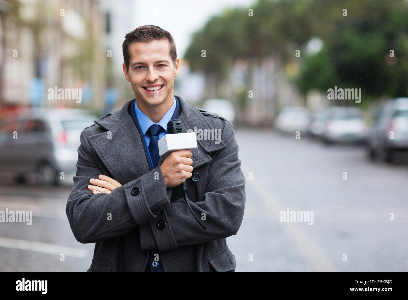 confident young news reporter working outdoors in the rain Stock Photo