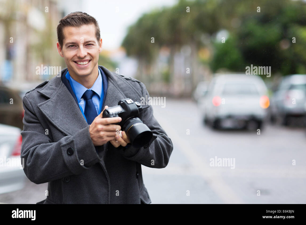 handsome journalist holding a camera in the city in the rain Stock Photo