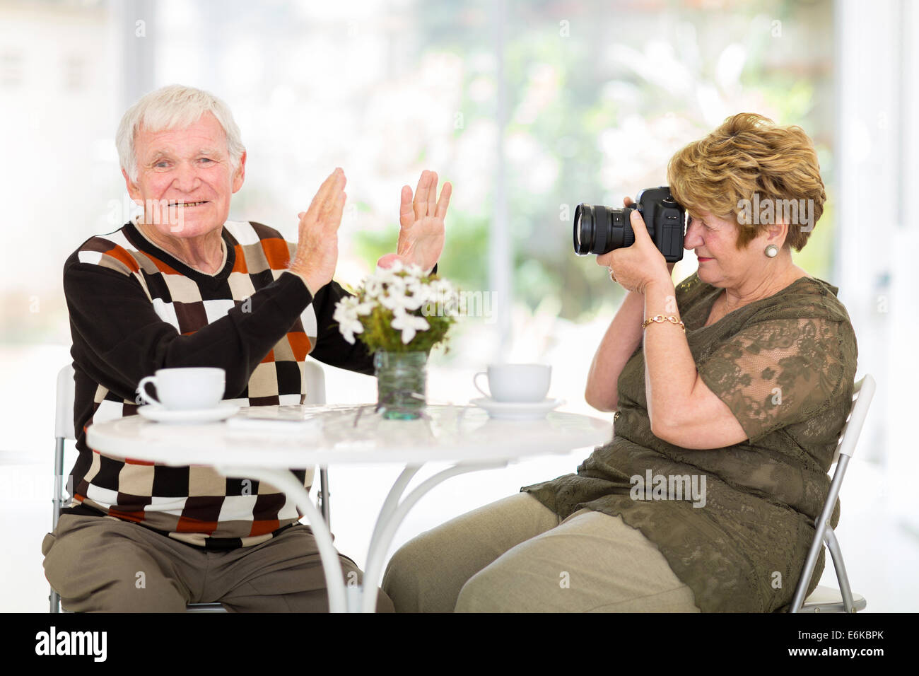 senior man refusing to be photographed by his wife at home Stock Photo