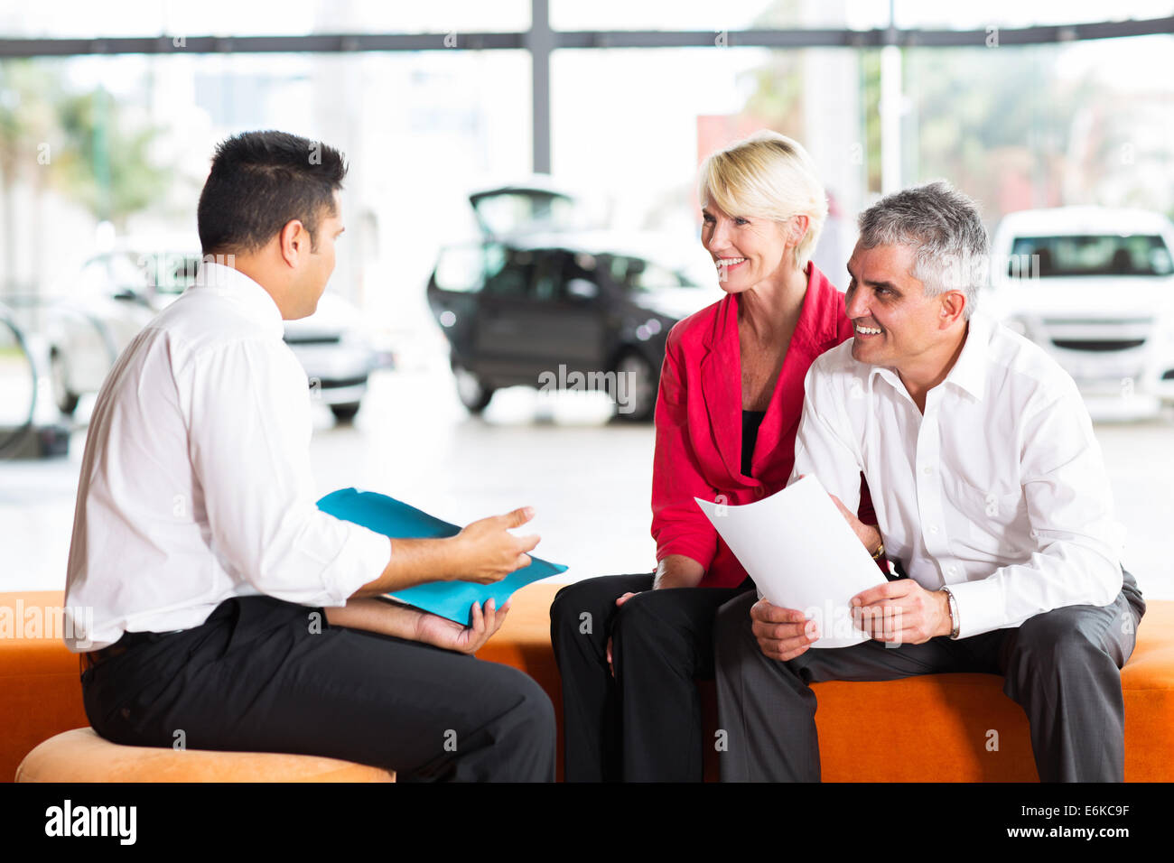 vehicle salesman explaining contract to senior couple before buying a car Stock Photo