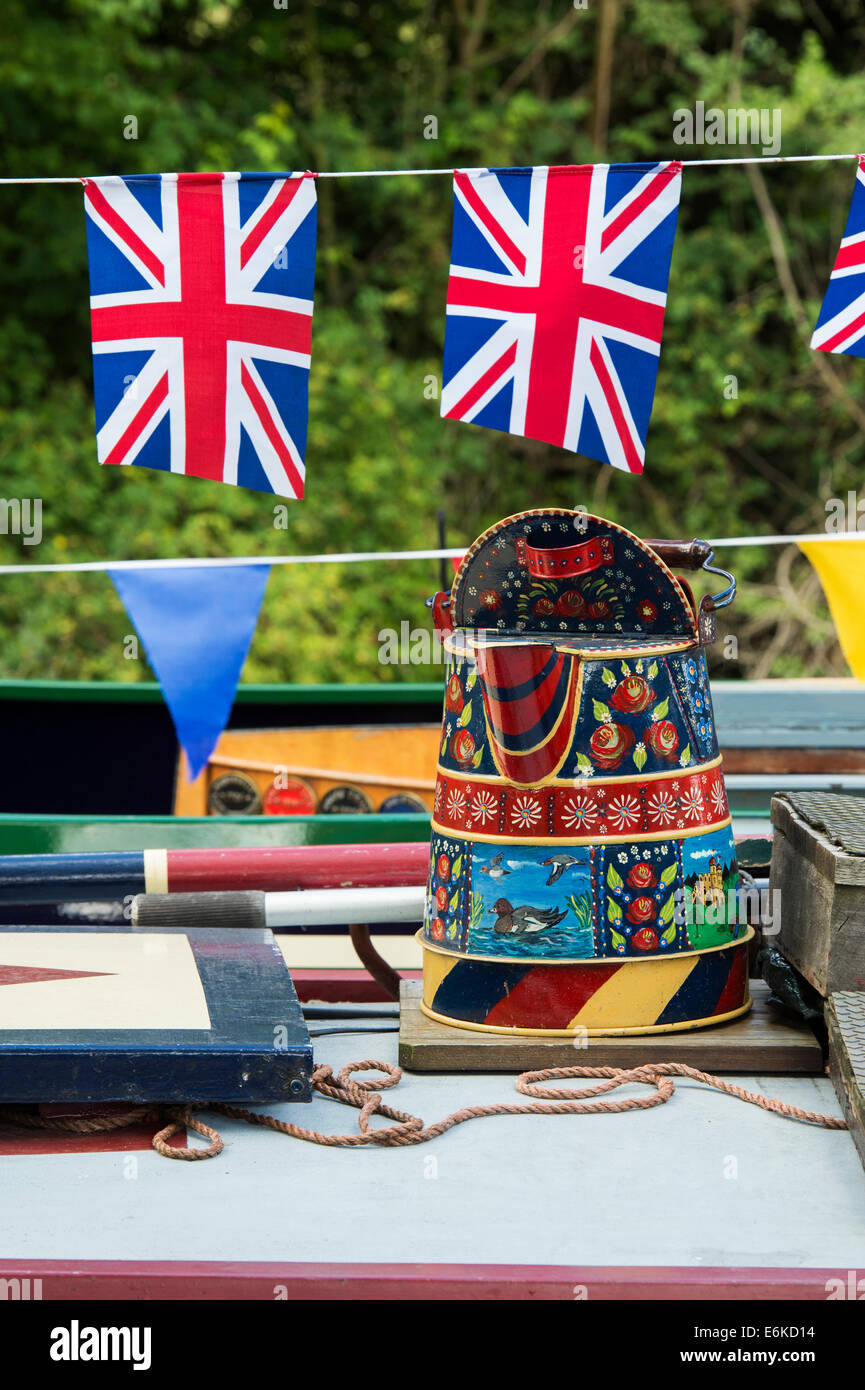 Canal Folk Art metal jugs on the roof of a narrowboat with union jack flag bunting on the Grand Union canal Stock Photo