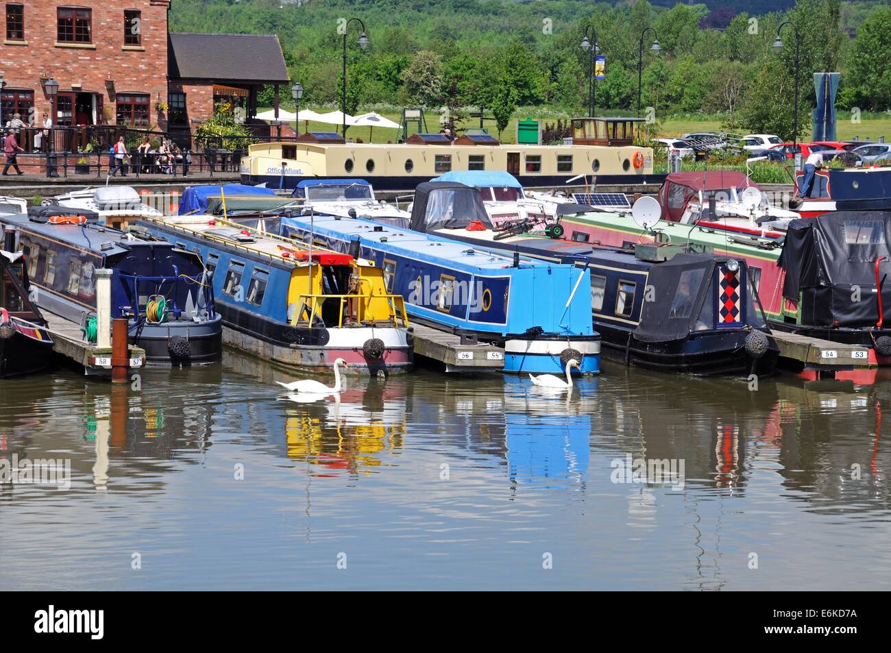 Narrowboats on their moorings in the canal basin with a bar to the rear