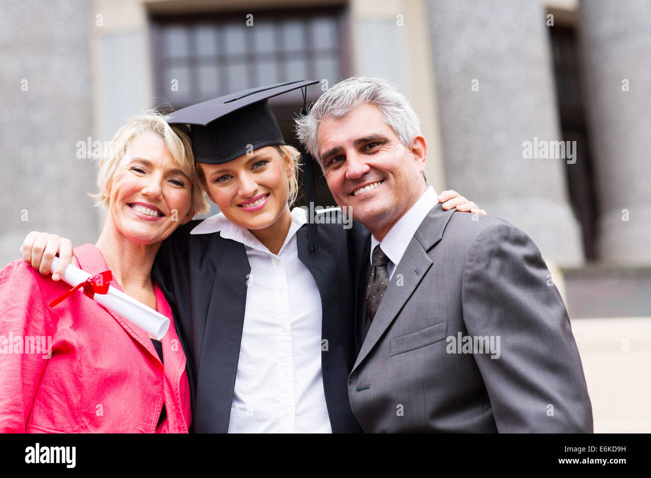 portrait of happy female university graduate and parents at ceremony Stock Photo
