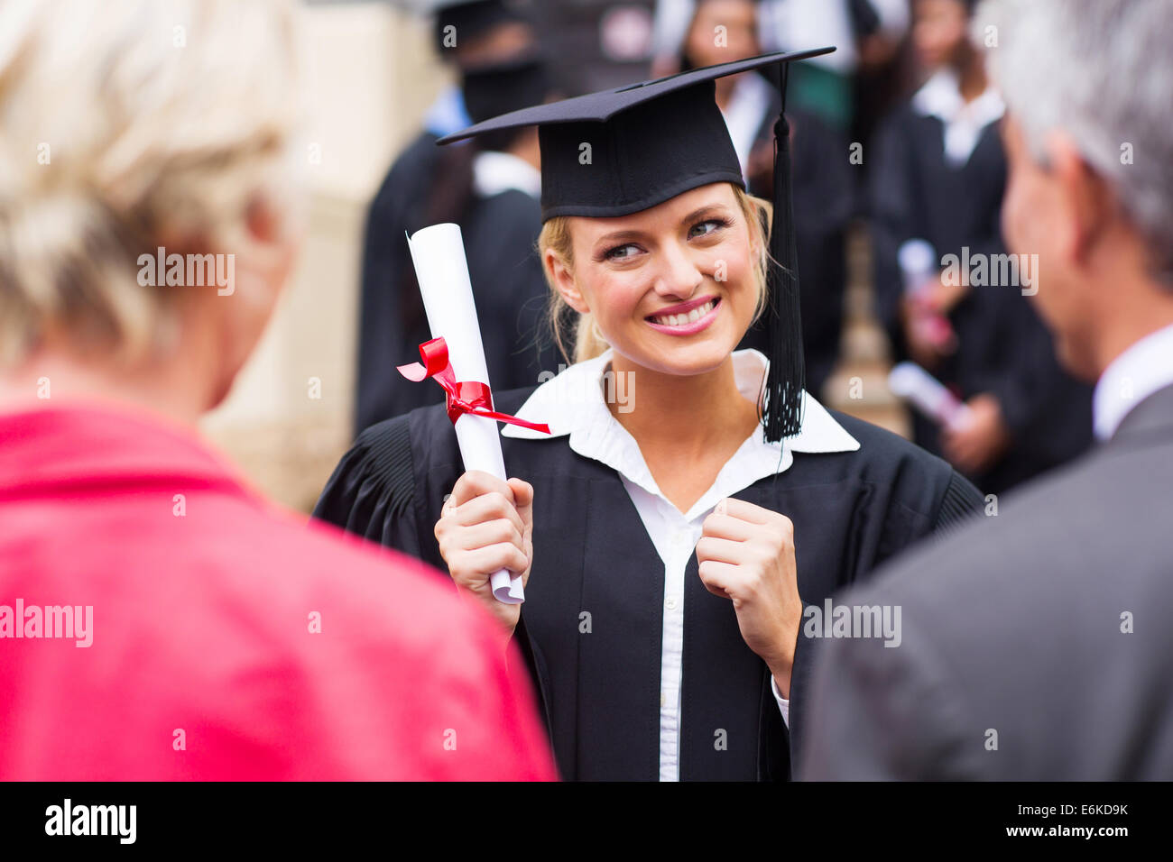 excited female college graduate looking at parents Stock Photo