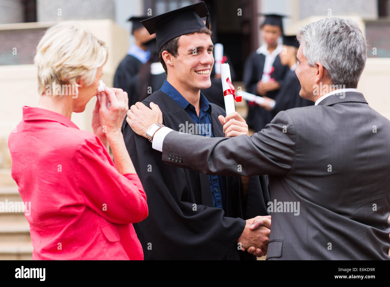 handsome male graduate being congratulated by his father at graduation ceremony Stock Photo
