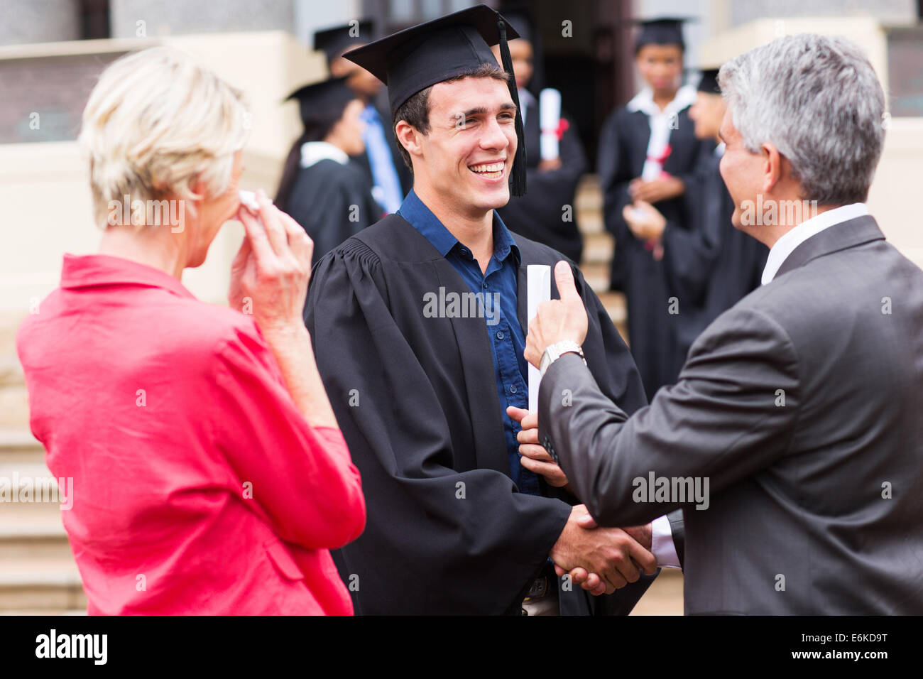 cheerful male graduate handshaking with his grandfather Stock Photo