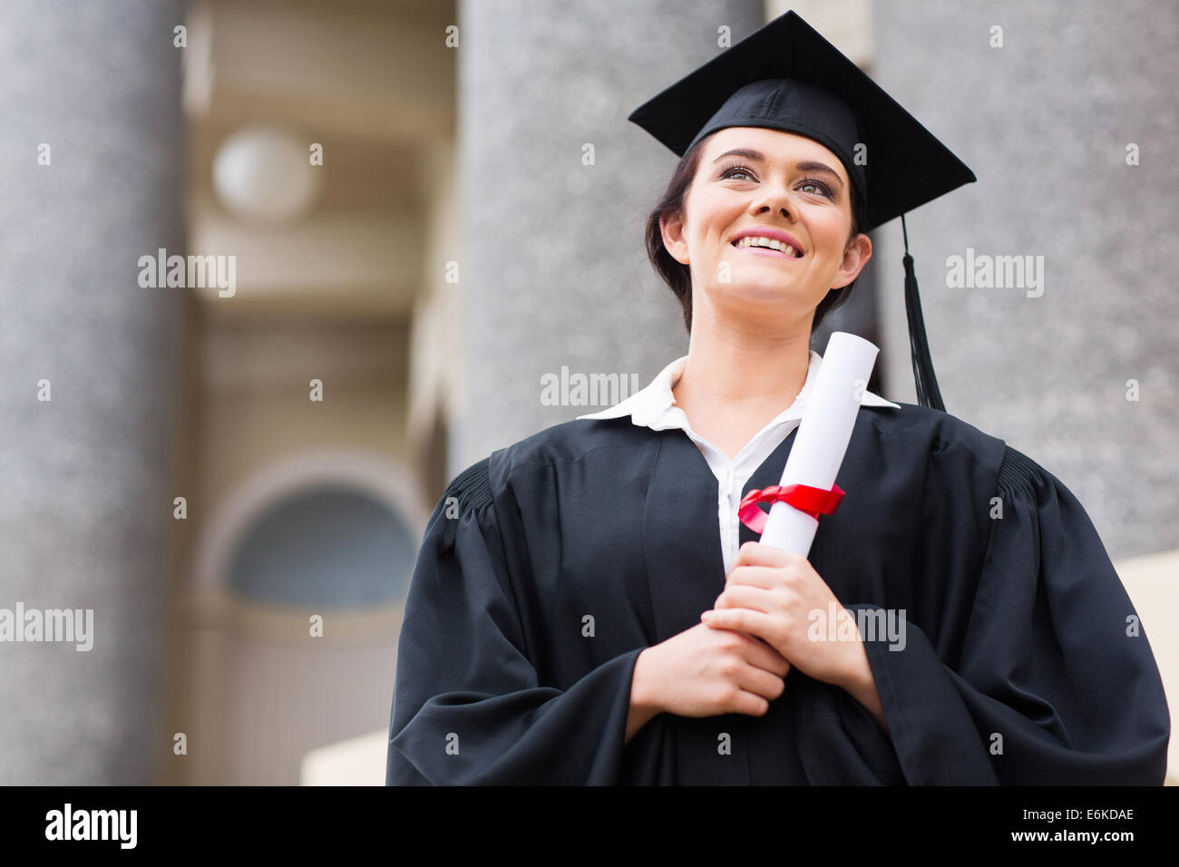 college student in graduation cap and gown in front of school building Stock Photo