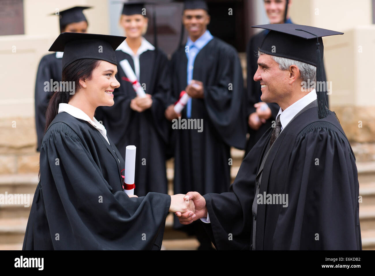 beautiful female graduate handshaking with dean Stock Photo