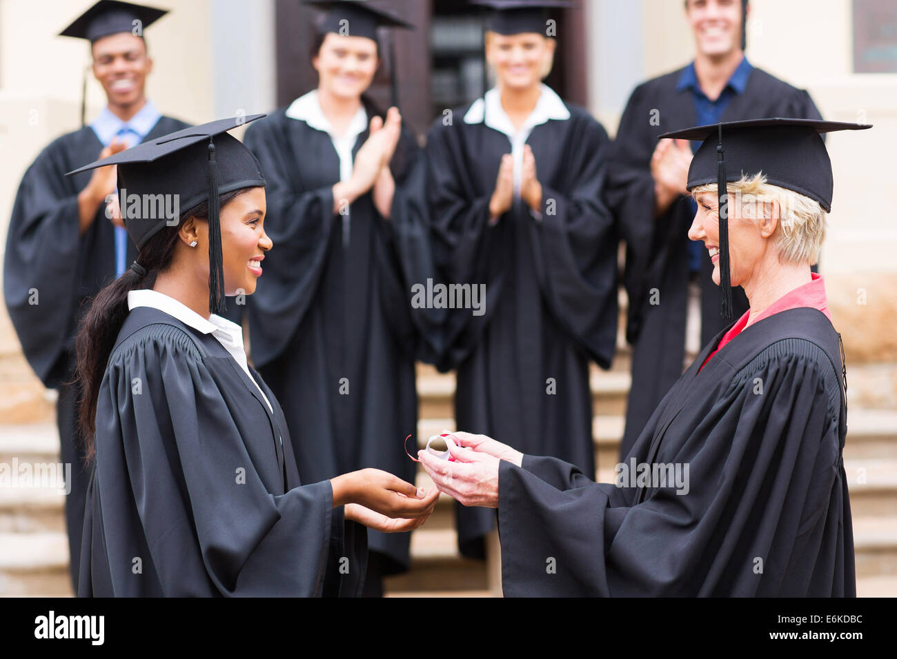 happy African American female graduate receiving diploma from dean Stock Photo