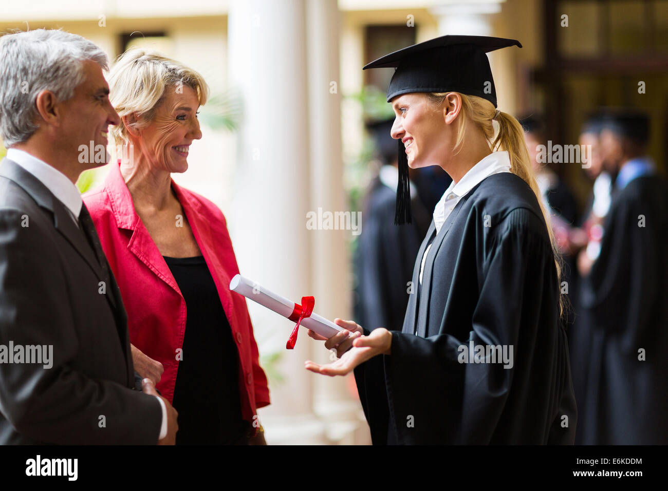 excited female graduate talking to parents on graduation day Stock Photo