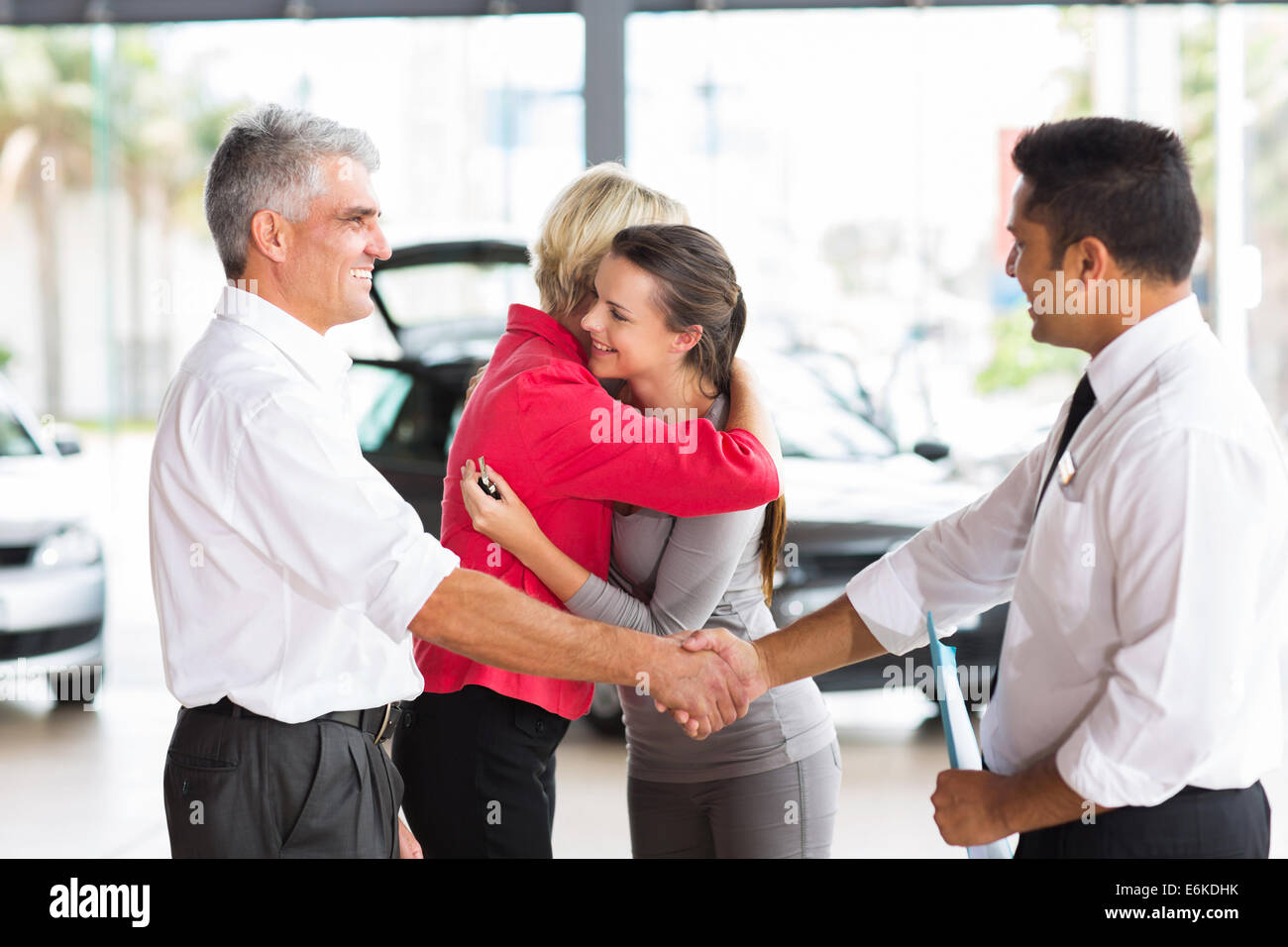senior man buying car for his daughter handshaking with dealer after the sale Stock Photo