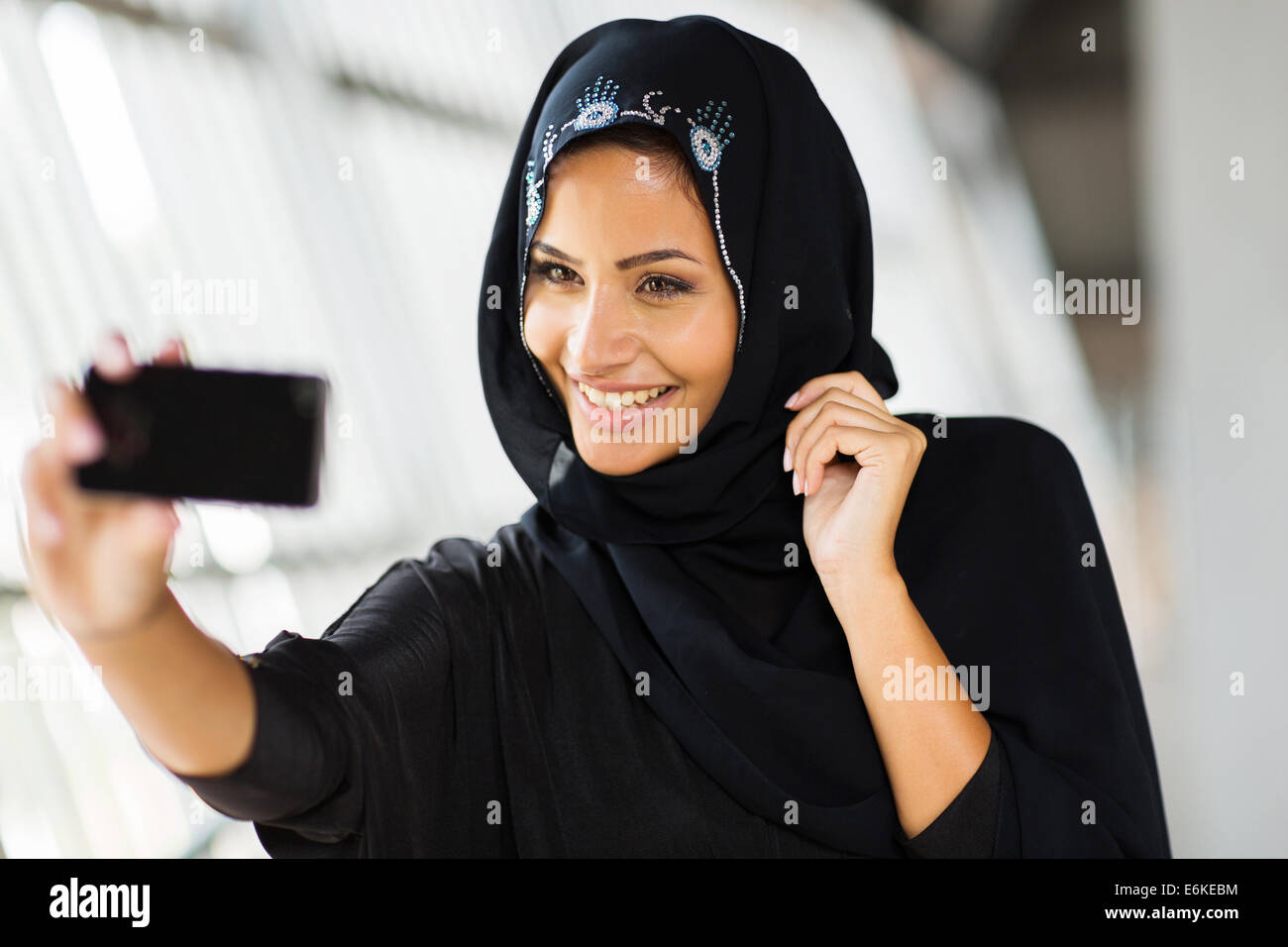 happy Arabian woman taking self portrait using cell phone Stock Photo ...