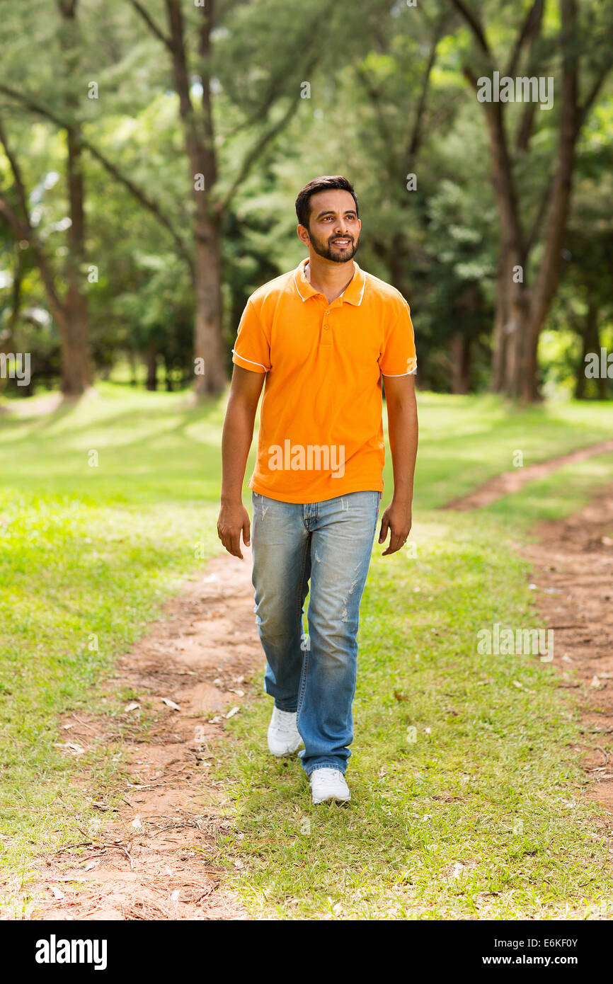 casual young Indian man walking in the park and looking away Stock Photo