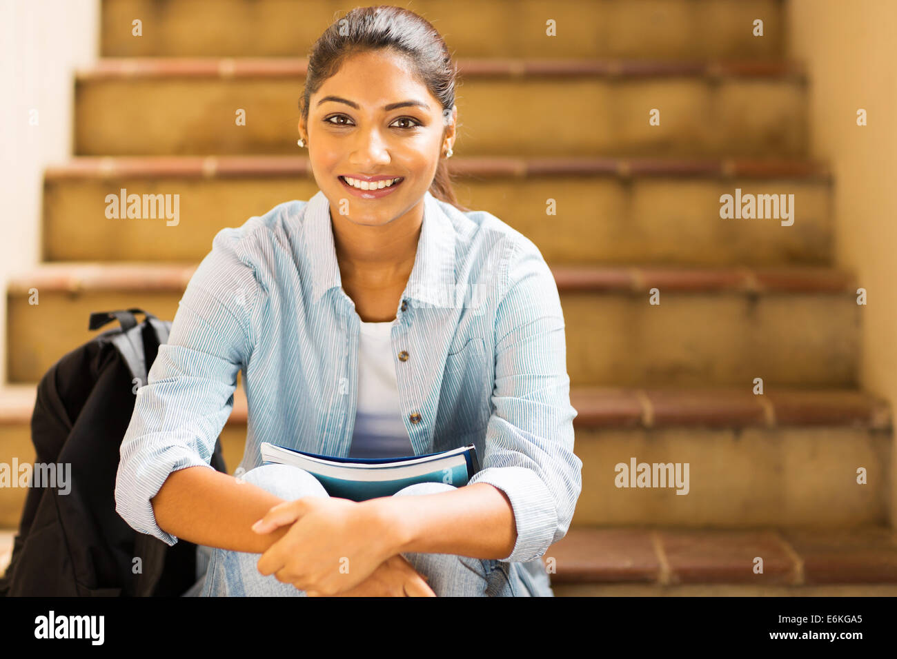 attractive female college student sitting on stairs Stock Photo