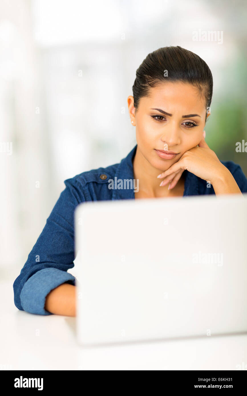 worried young woman looking at computer screen Stock Photo
