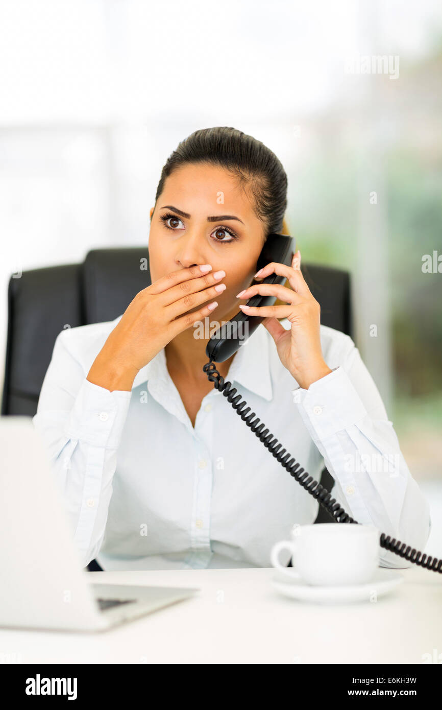 pretty young office worker receiving shocking news on the phone Stock Photo