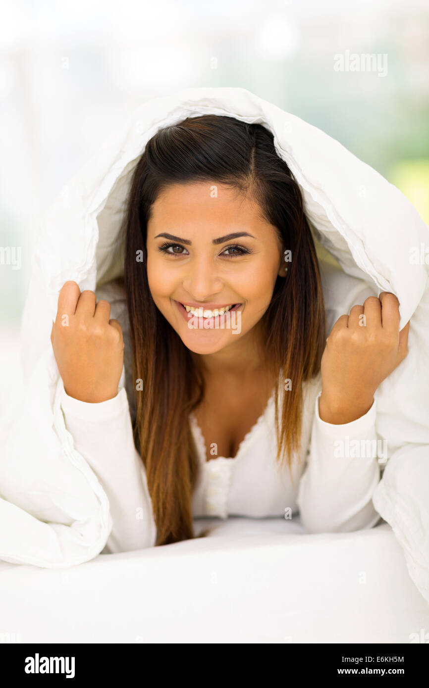 happy woman lying under duvet on bed Stock Photo