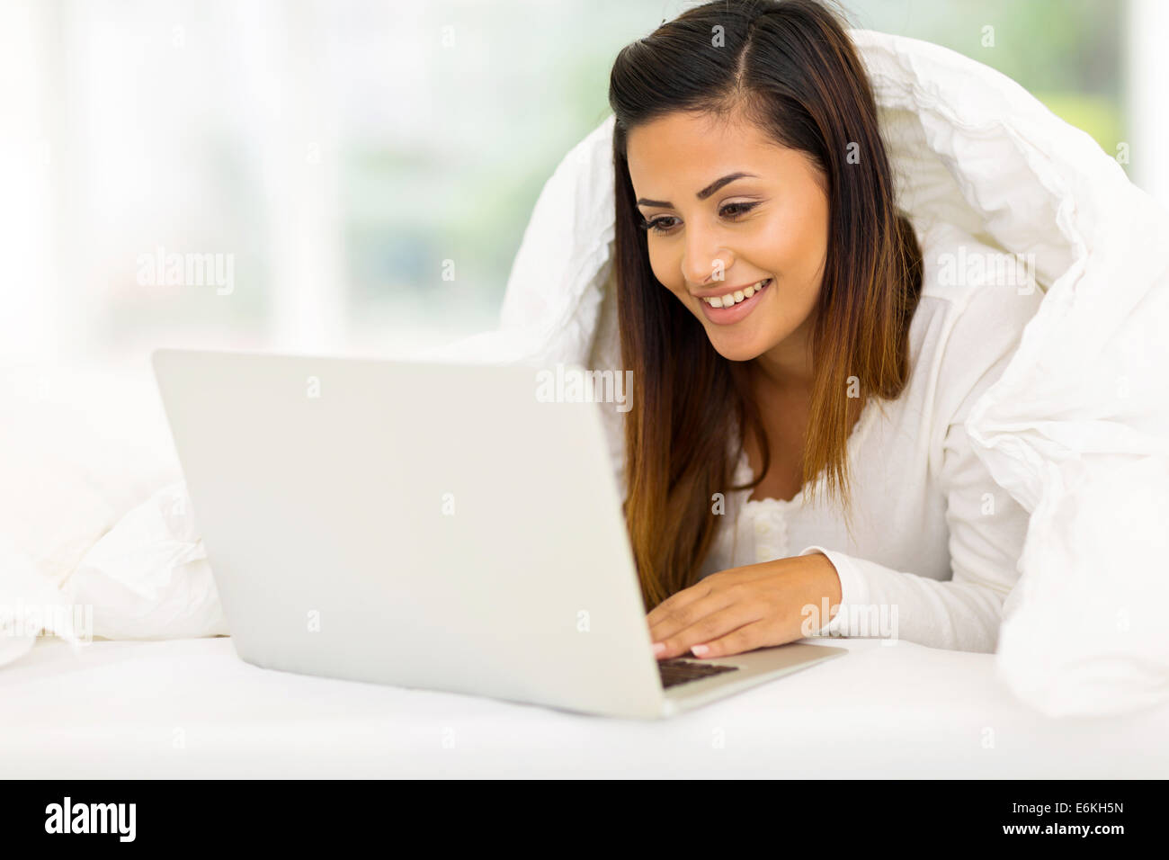 gorgeous woman using laptop computer while lying on her bed Stock Photo ...
