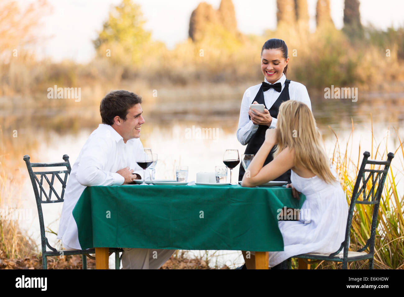 beautiful young couple place dinner order to waitress outdoors Stock Photo