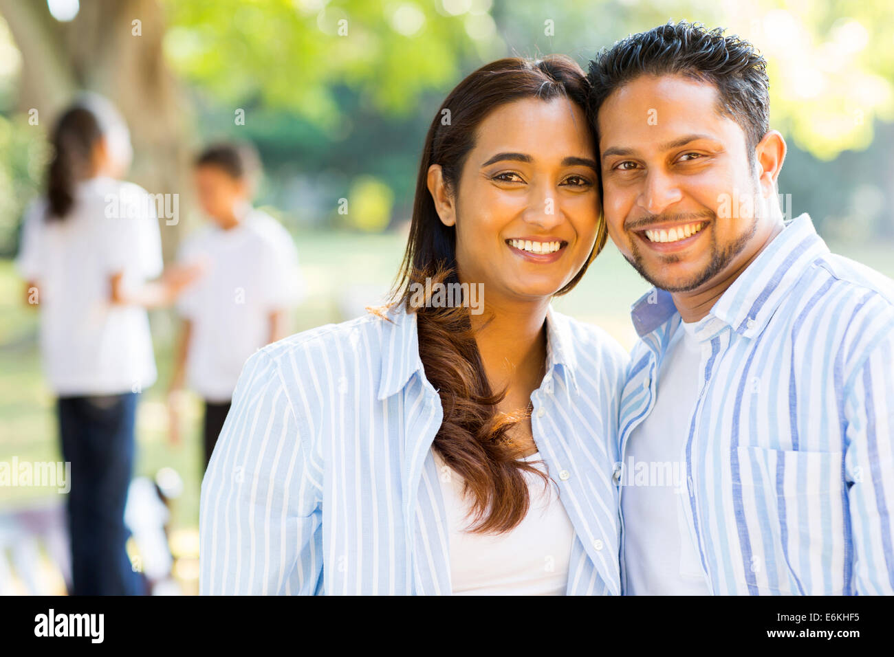 happy Indian couple standing in front of children outdoors Stock Photo