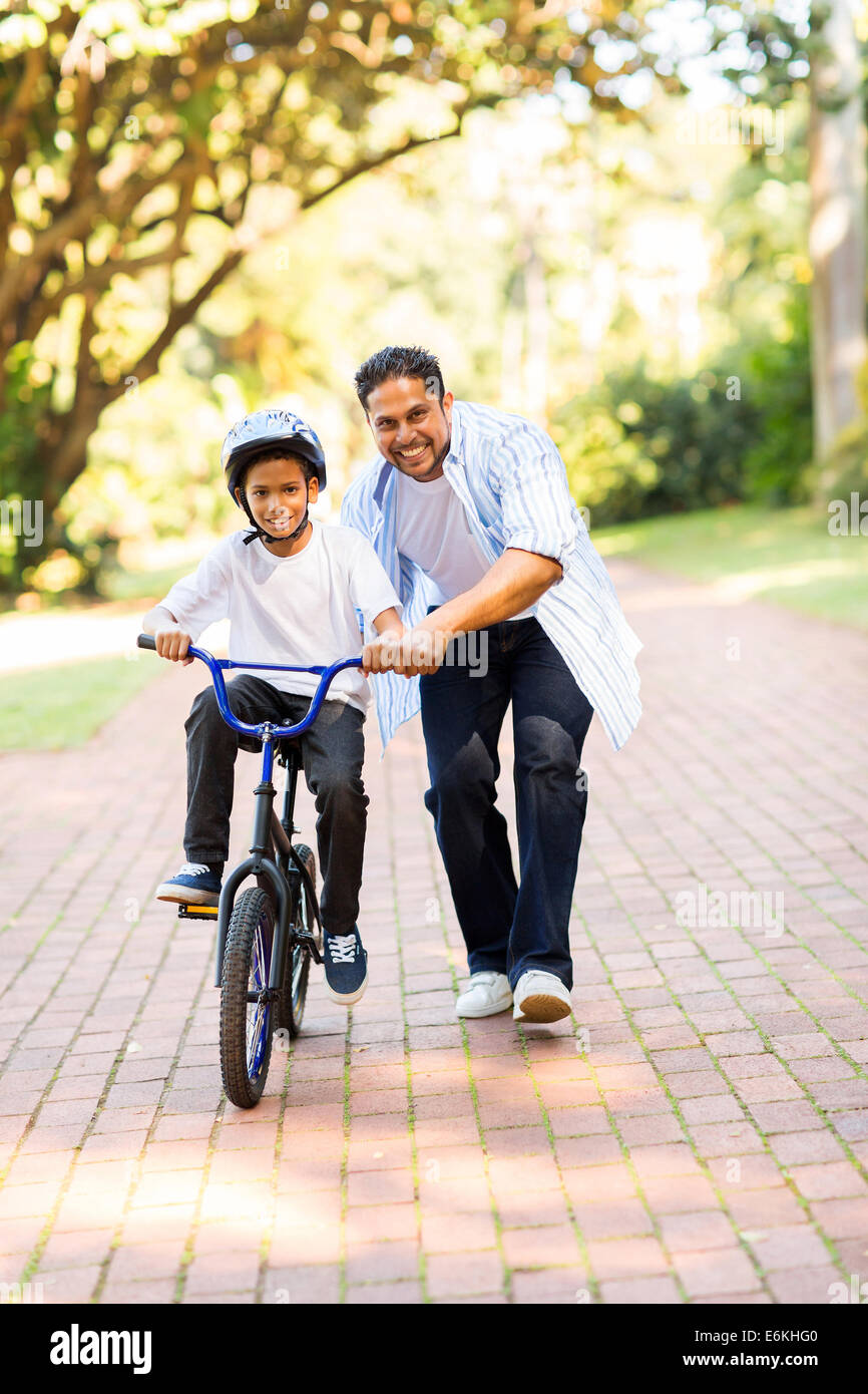 happy Indian father teaching his son to ride a bicycle at the park