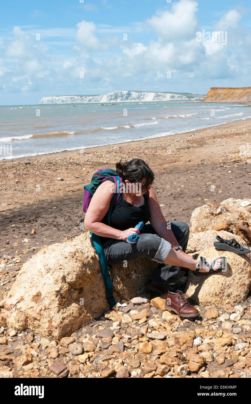 Woman changing her boots. Brook Bay lies at the southern end of the Hamstead Trail that crosses the Isle of Wight. Stock Photo