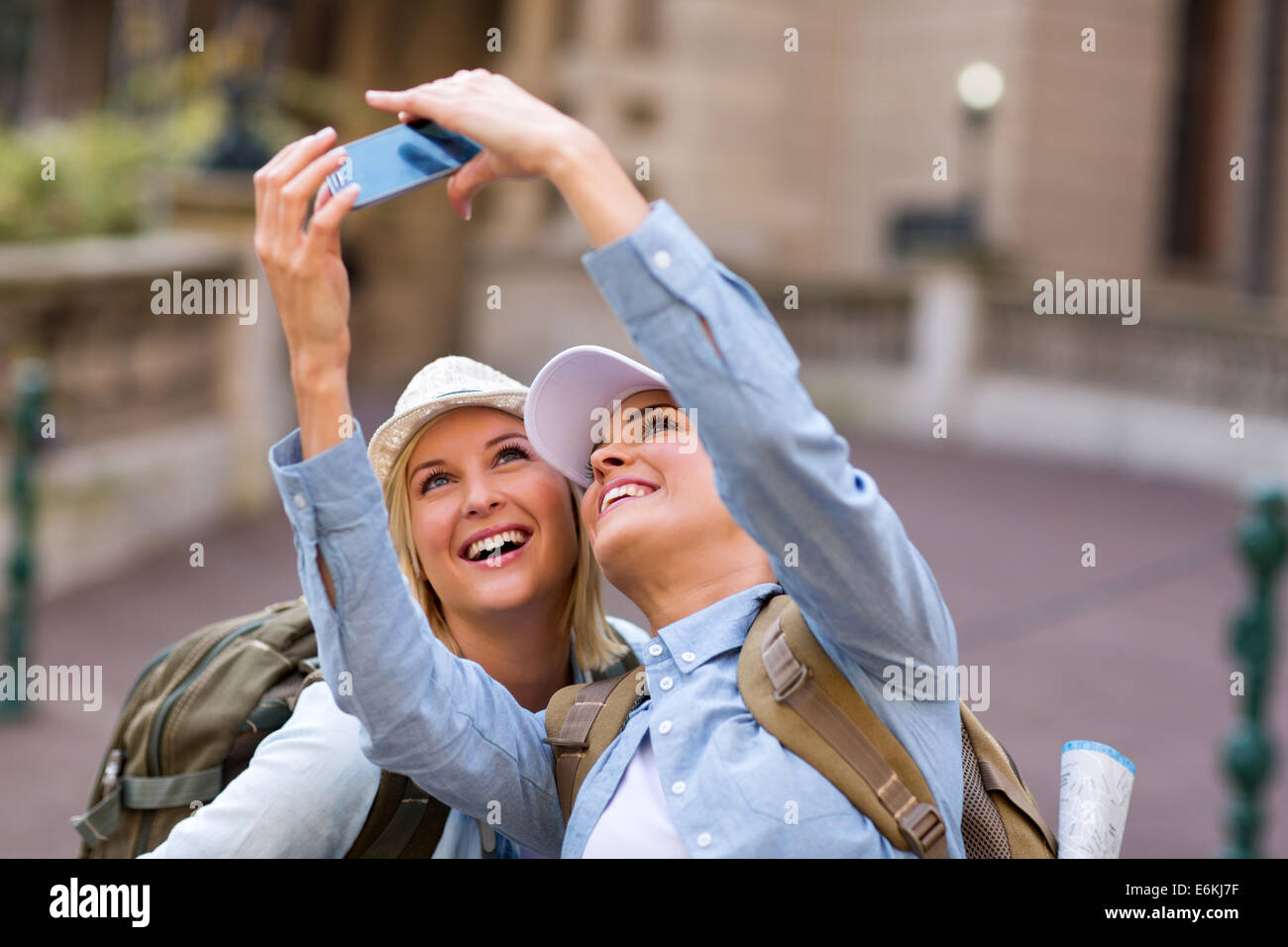 cheerful friends taking self portrait using cell phone at tourist's attraction Stock Photo