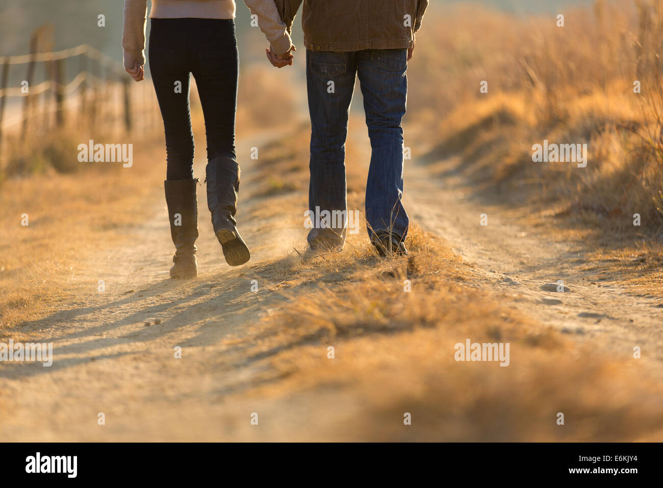 young couple holding hands walking on autumn rural path in the morning Stock Photo