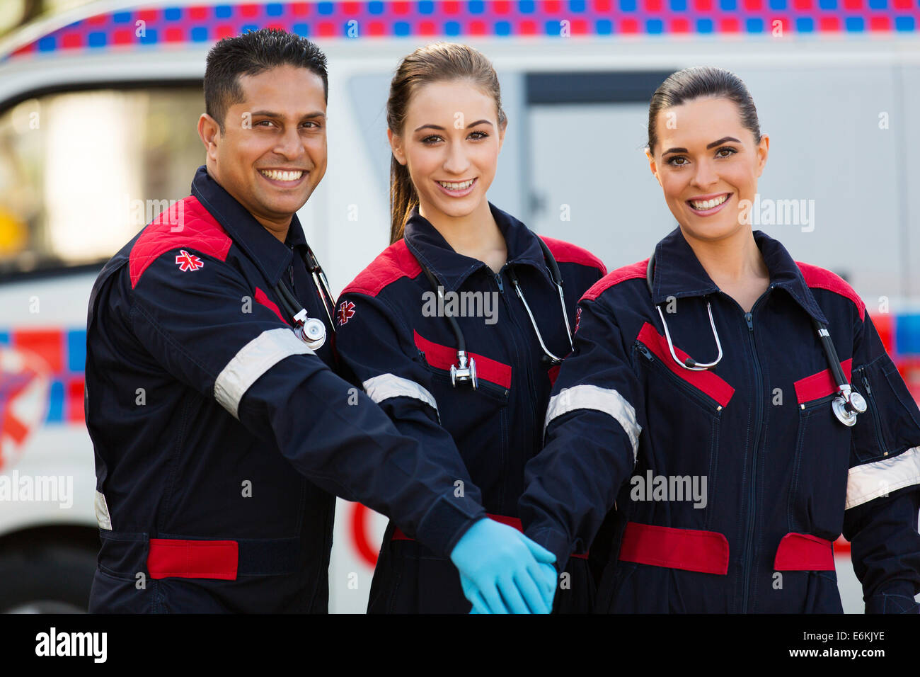 group of paramedics hands together in front of ambulance Stock Photo