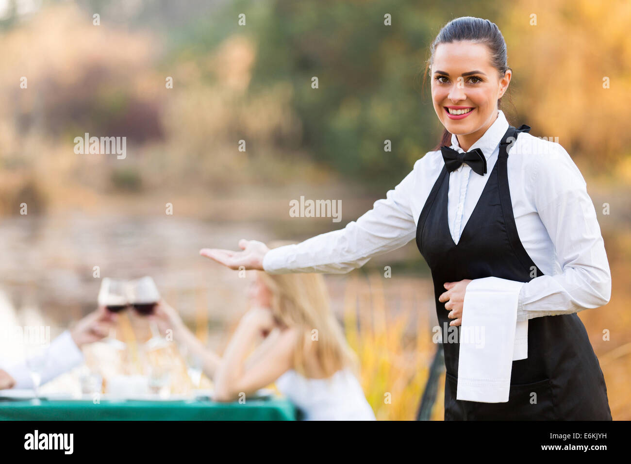 pretty young waitress welcomes customers to romantic dinning environment Stock Photo