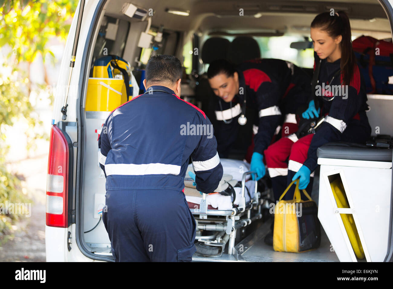 ambulance team pulling a stretcher out of vehicle Stock Photo