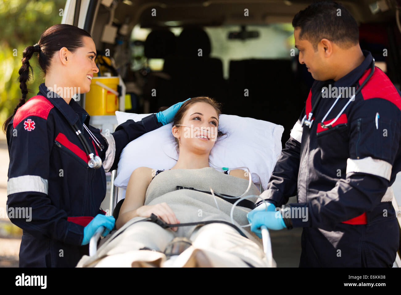 friendly paramedic comforting young patient before transporting her to hospital Stock Photo