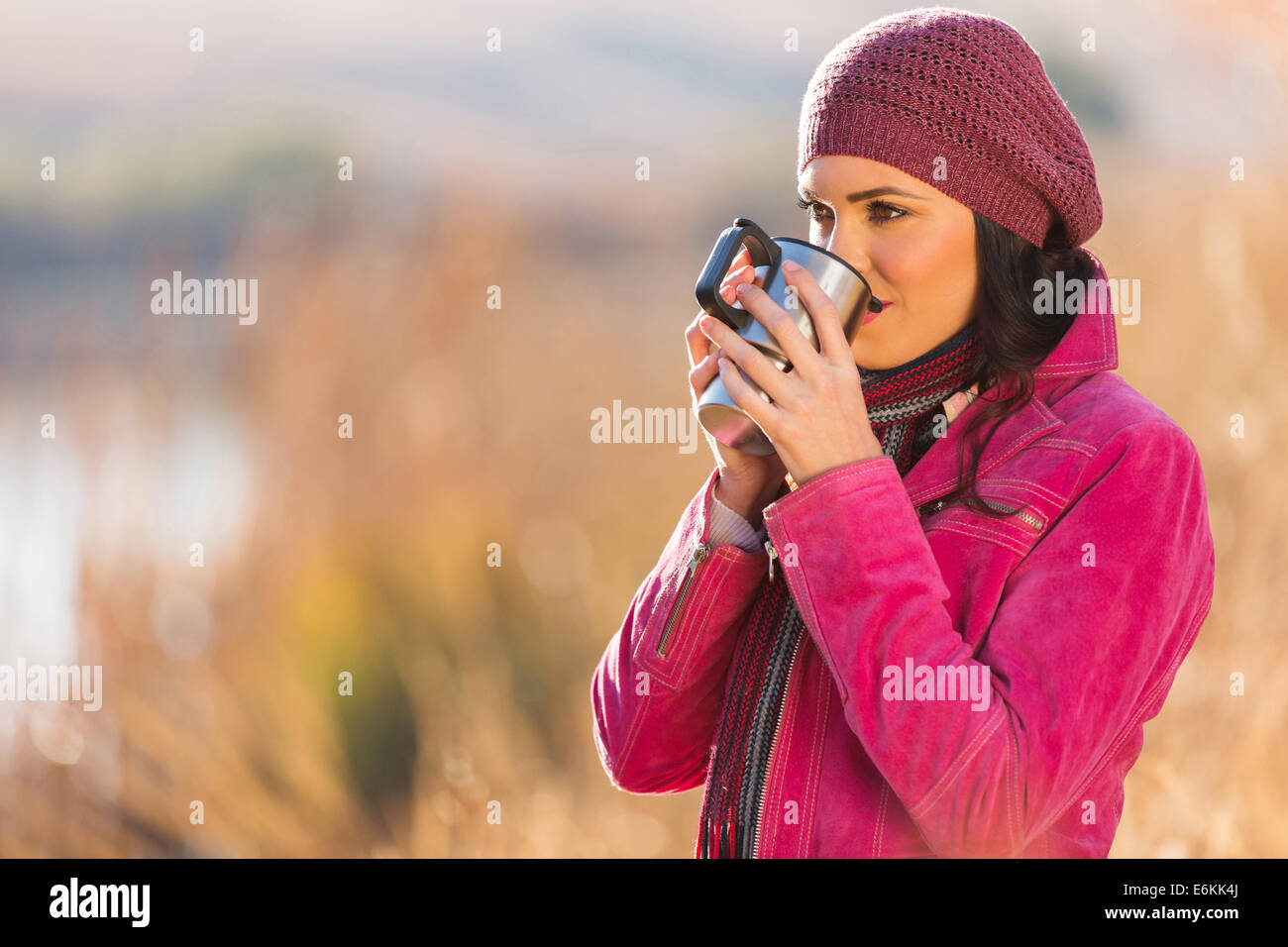girl drinking coffee outdoors by the lake in autumn Stock Photo