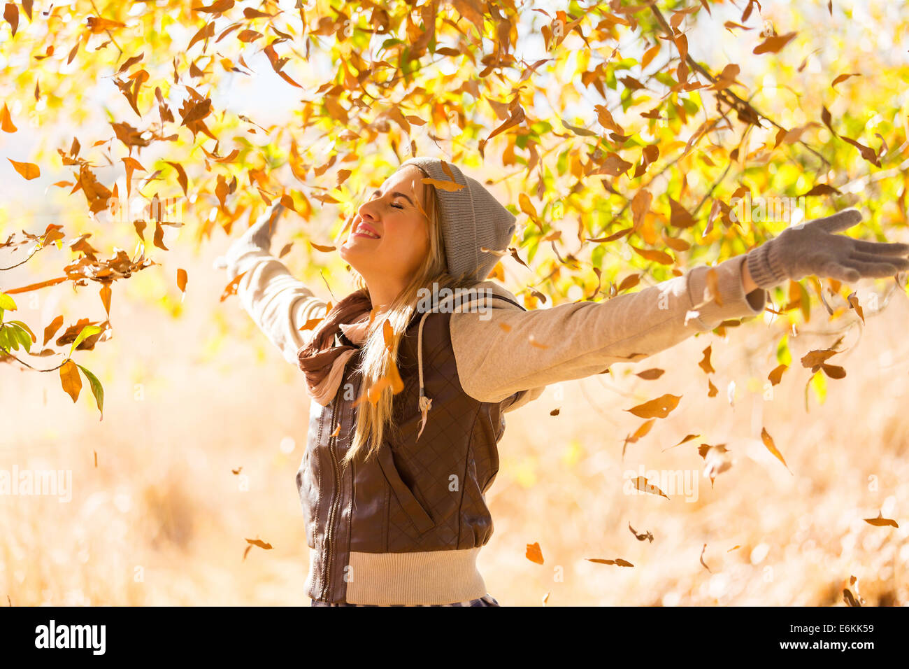 autumn leaves falling on happy young woman in forest Stock Photo