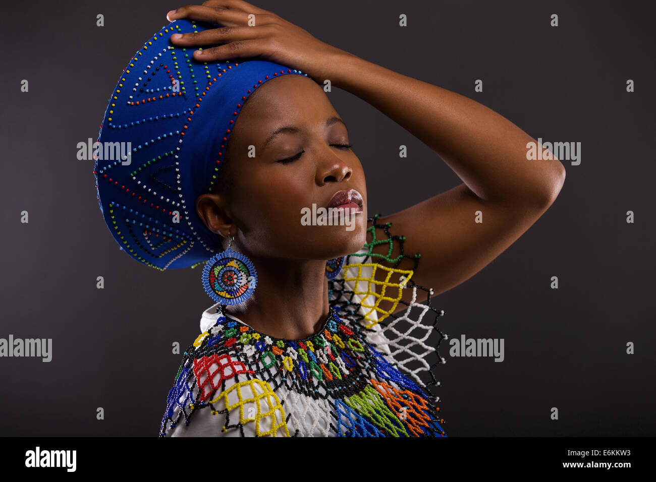 attractive African woman in traditional clothes with eyes close isolated on black background Stock Photo
