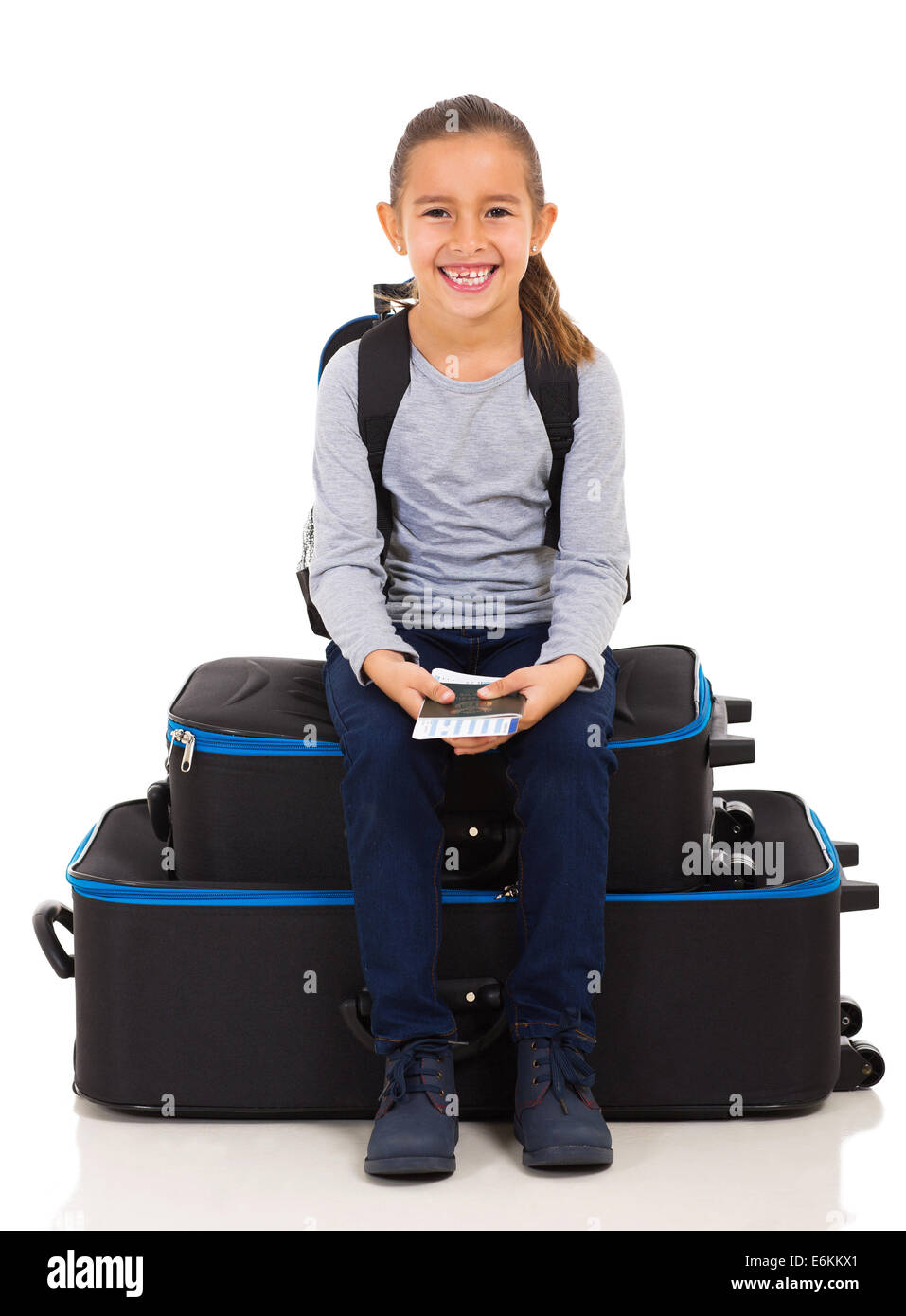 happy little girl sitting on luggage bags and holding boarding pass with passport Stock Photo