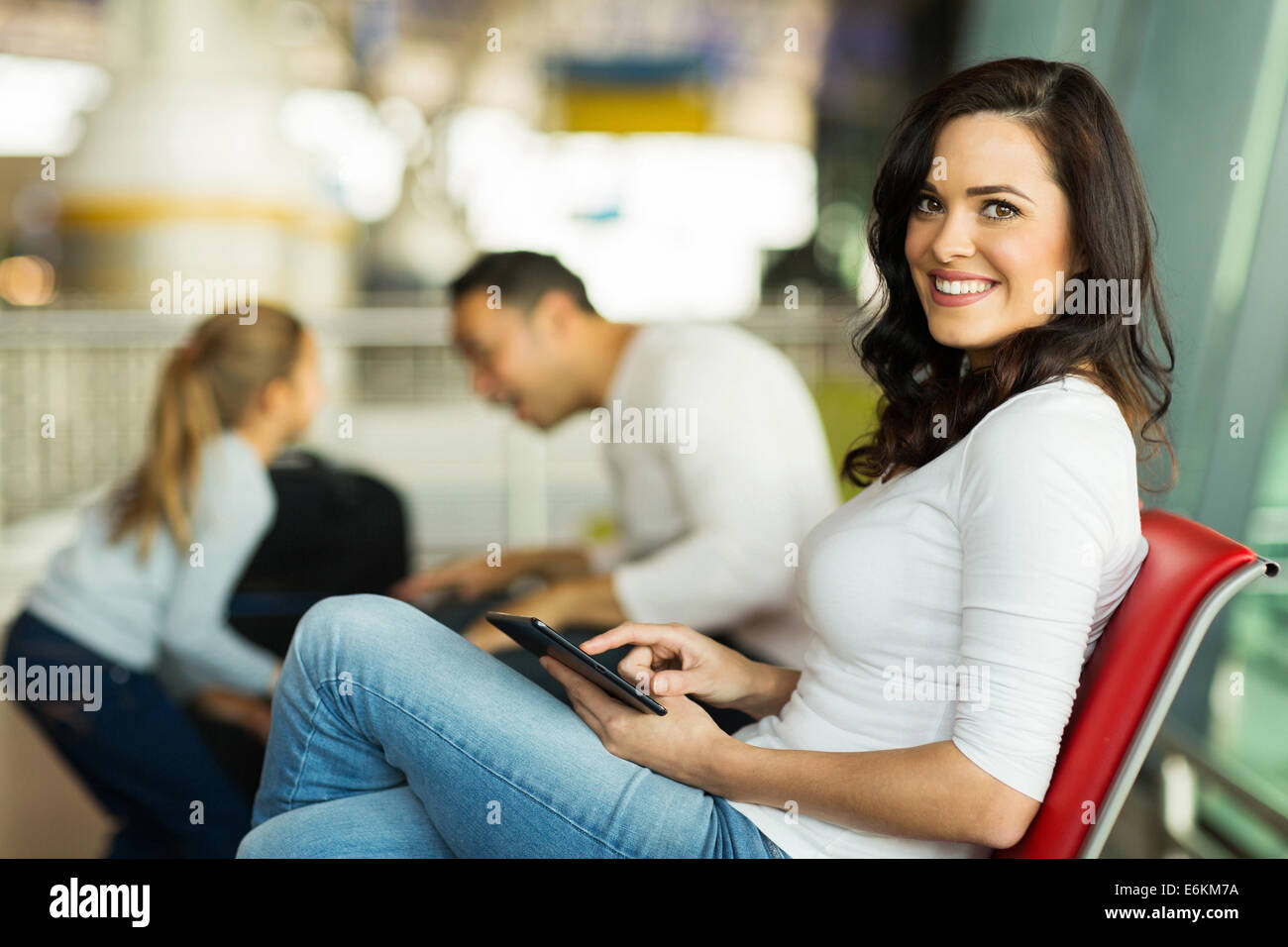 pretty woman holding tablet computer relaxing at airport while her husband playing with kid Stock Photo