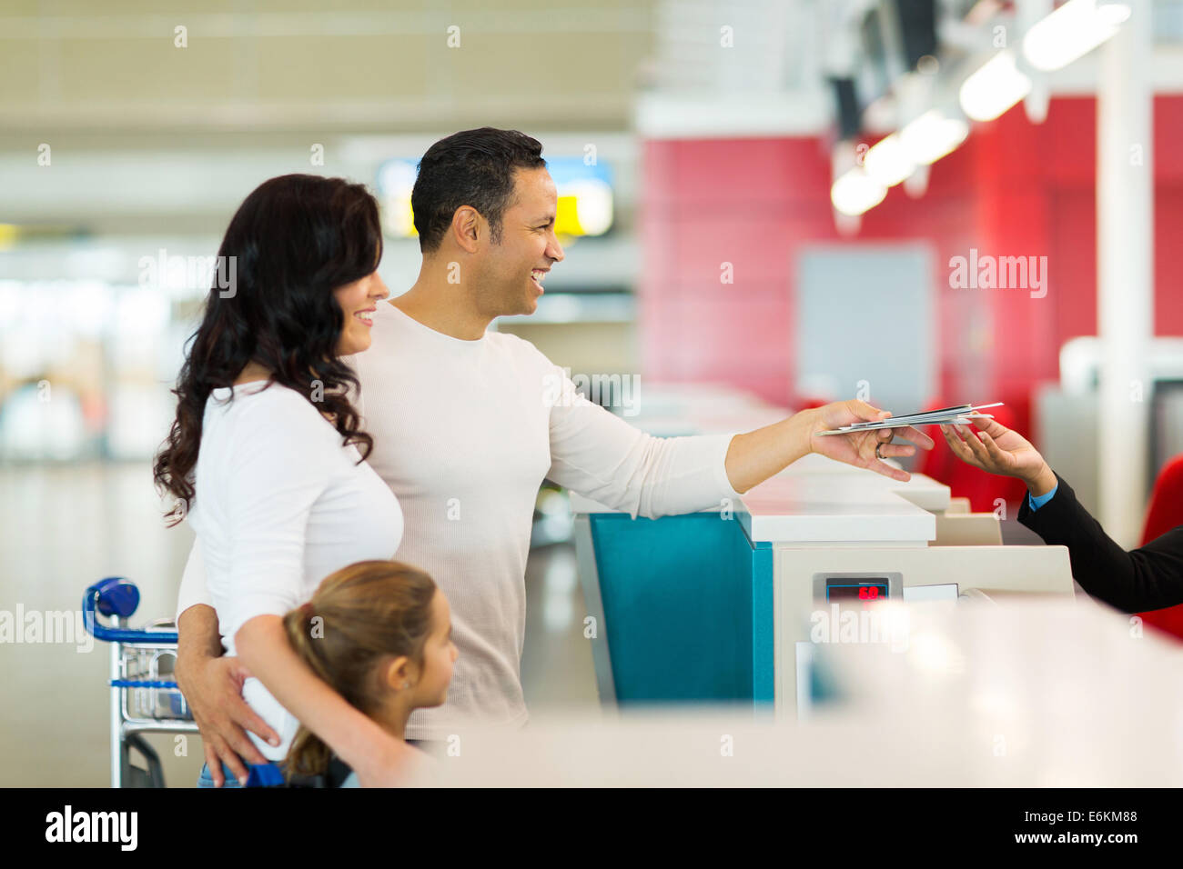 cheerful family handing over air ticket at airport at check in counter Stock Photo