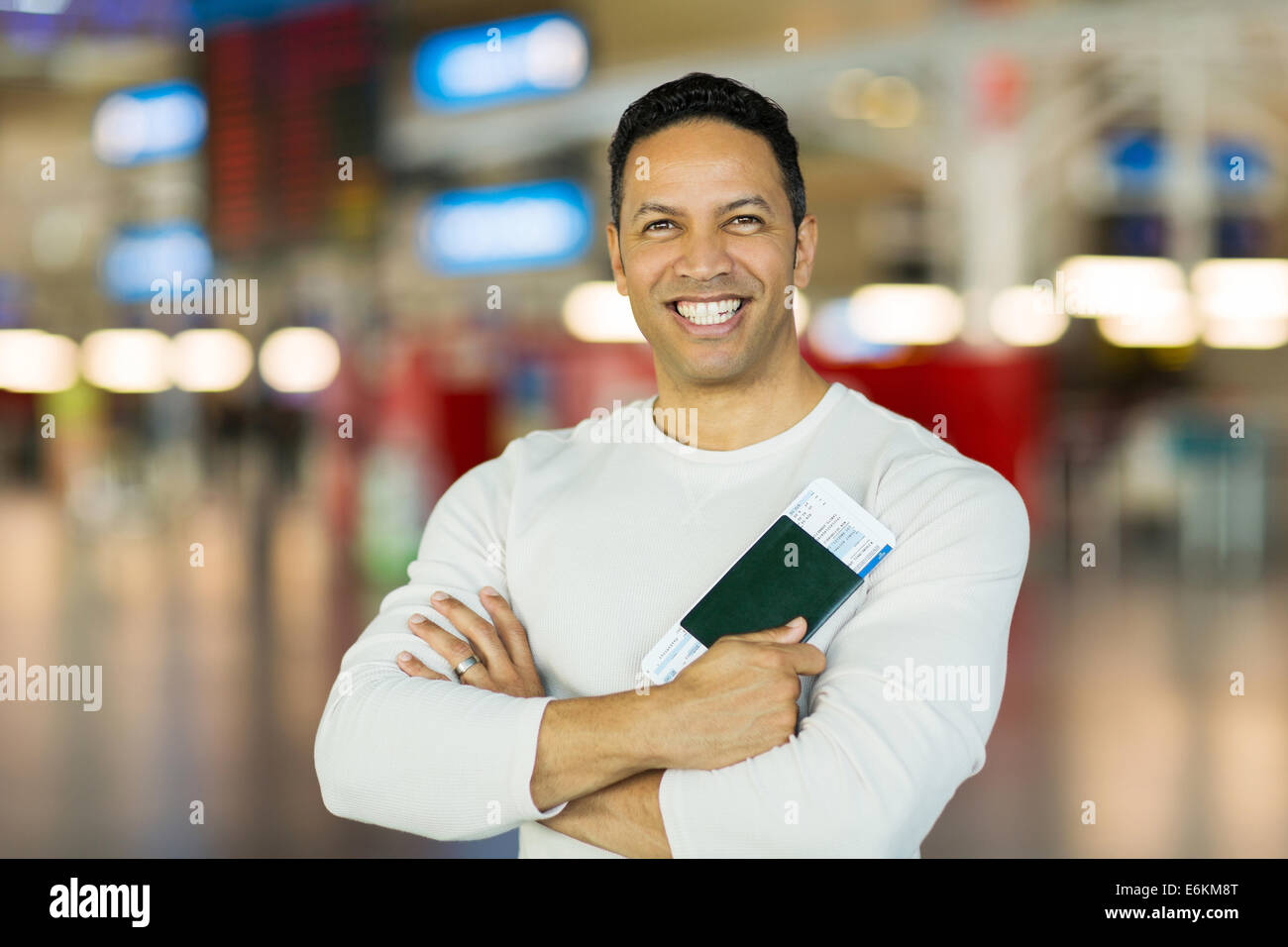 mid age man holding passport and boarding pass at airport Stock Photo