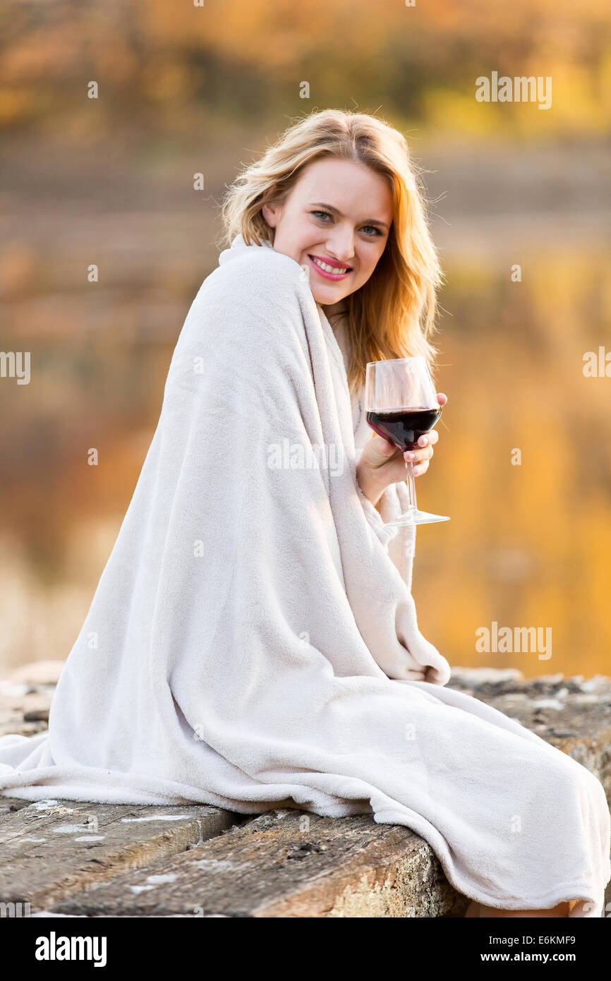 pretty woman sitting on a pier and enjoying wine at sunset Stock Photo