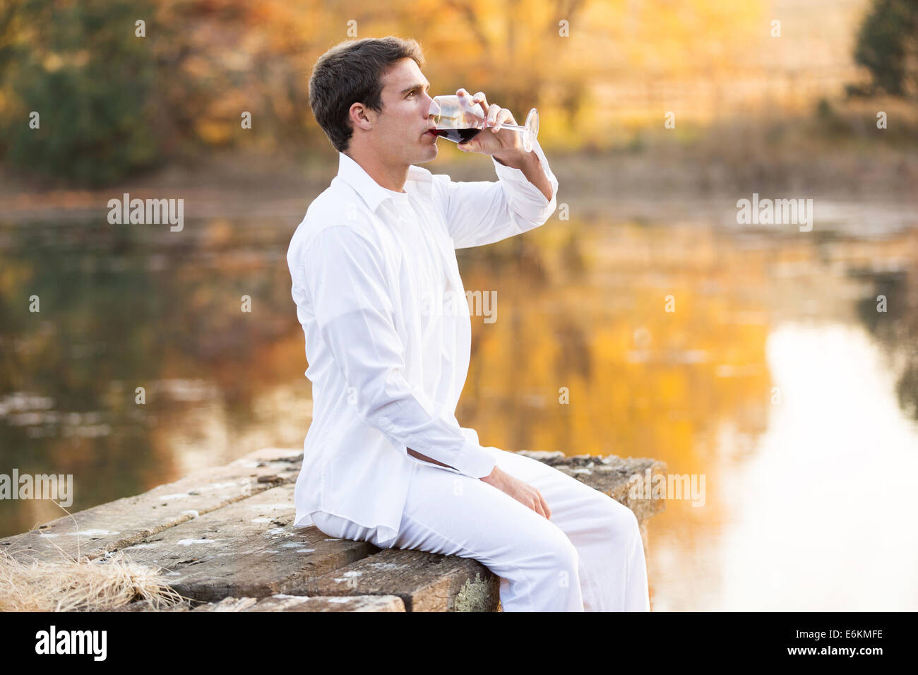 peaceful young man drinking red wine outdoors at sunset Stock Photo