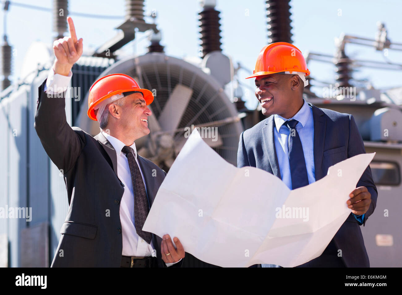 happy managers discussing blueprint at electrical substation Stock Photo