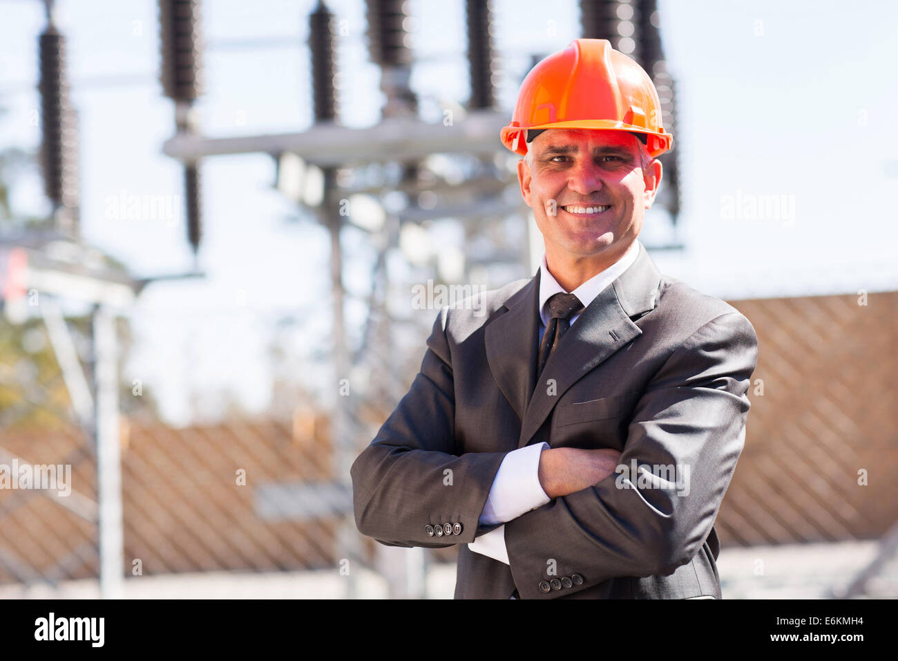 senior male industrial engineer in electricity substation with arms crossed Stock Photo