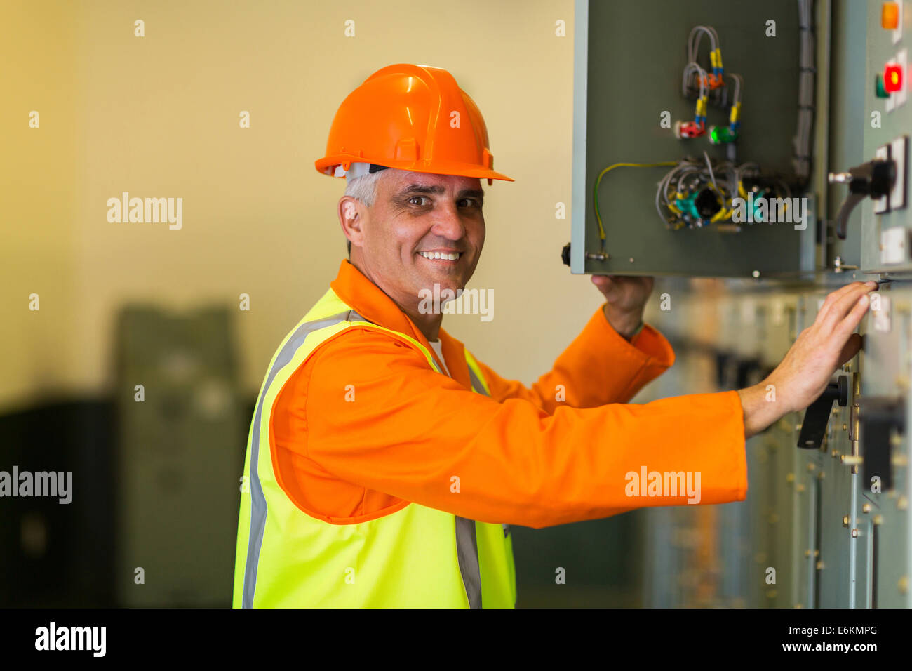 happy mid age electrician checking industrial control box Stock Photo