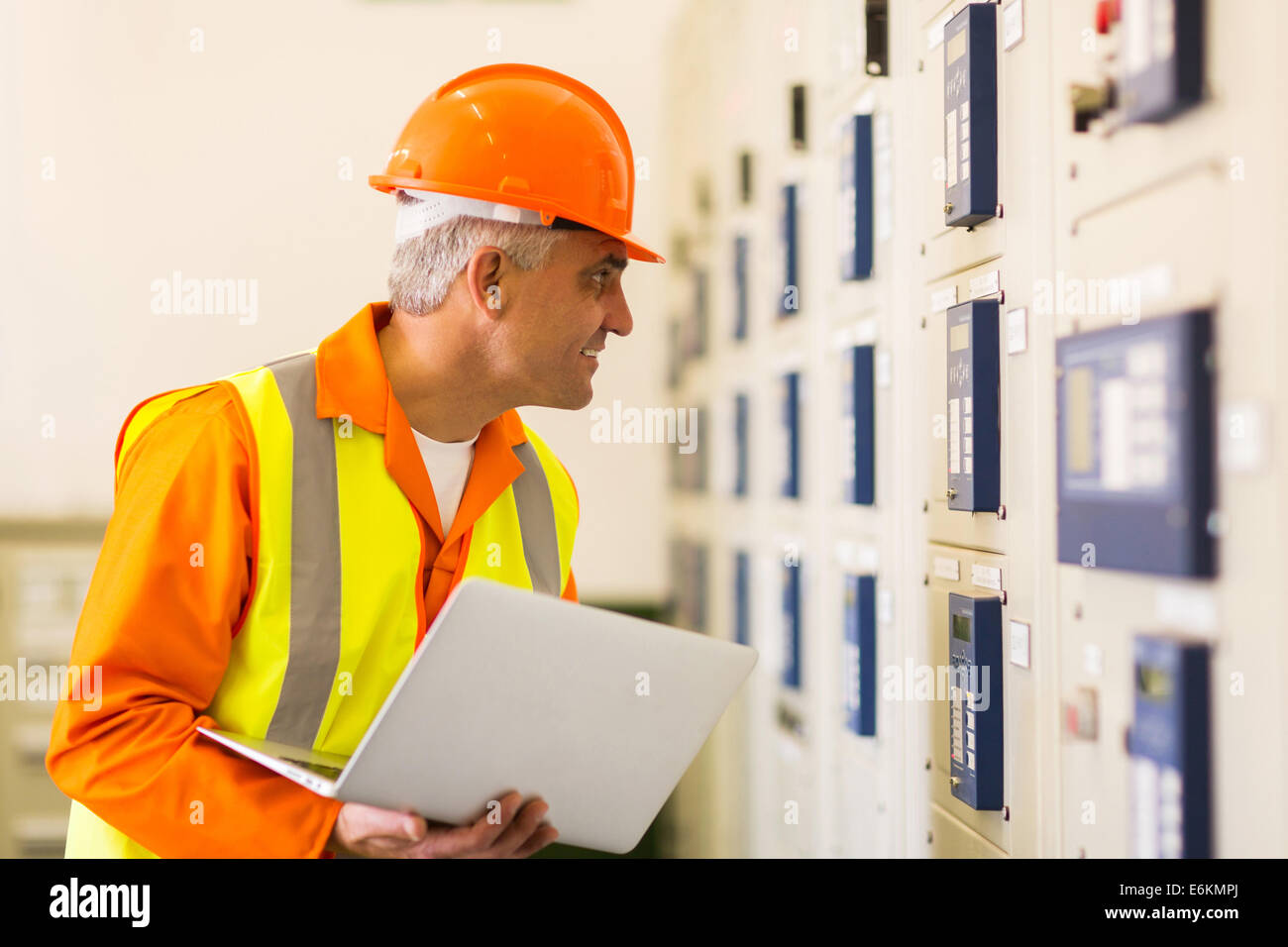 middle aged industrial electrician working in power plant control room Stock Photo