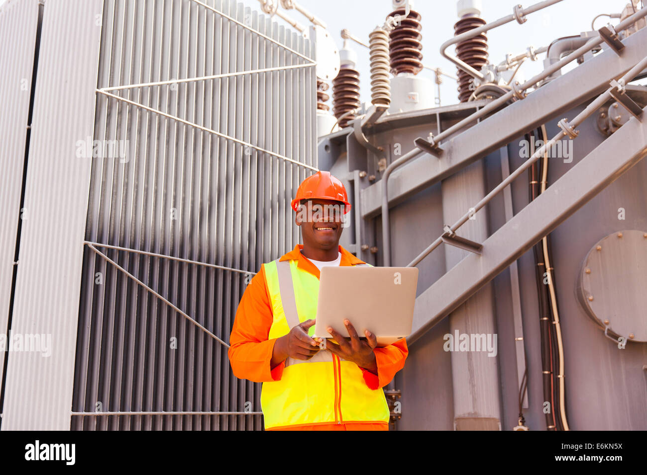 African electrician using laptop in front of transformer Stock Photo