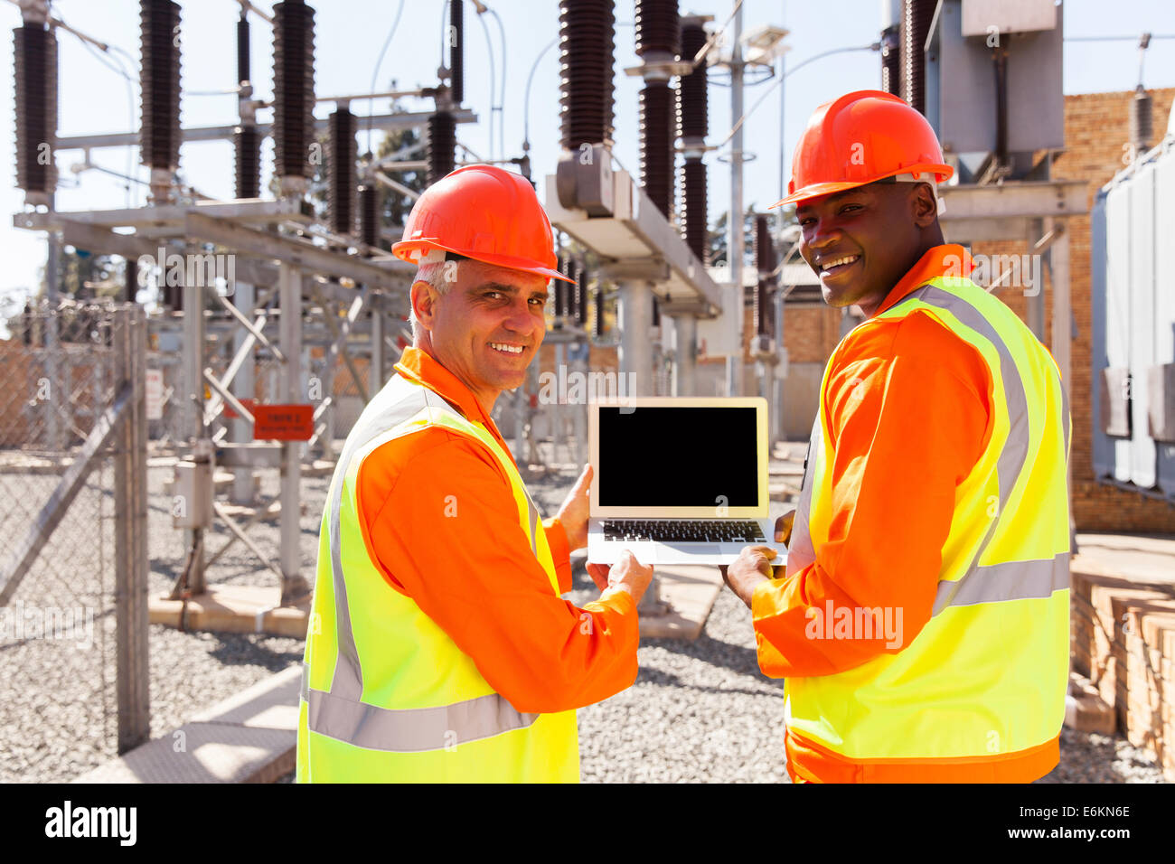 happy electrical engineers holding laptop computer in power plant Stock ...
