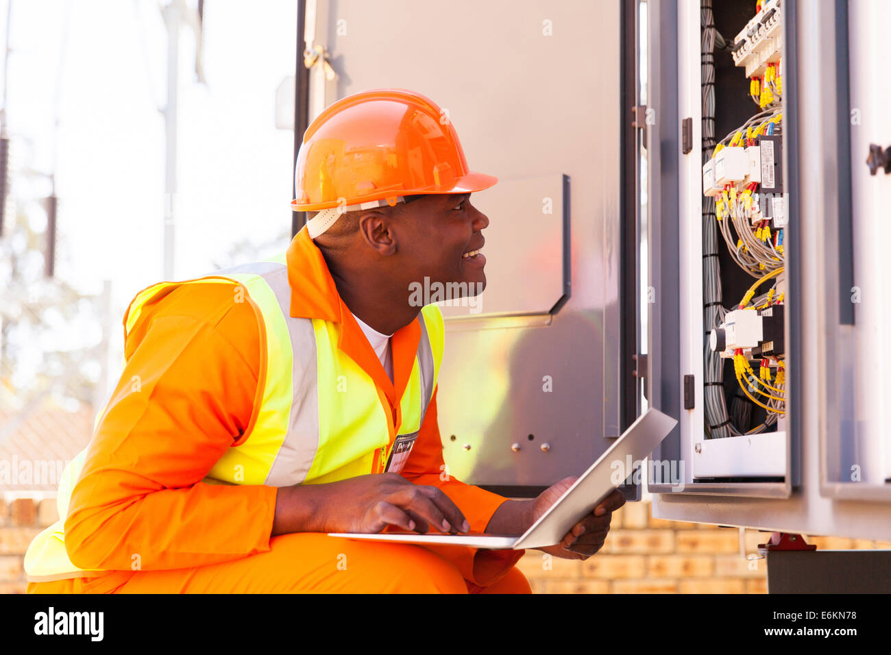 experienced African electrician checking computerized machine status with laptop Stock Photo