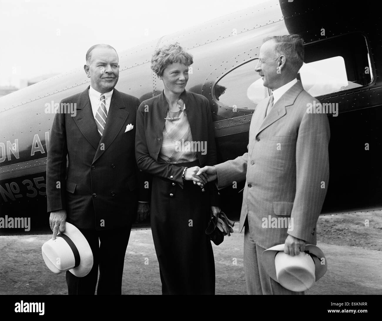 Vintage photo of American aviation pioneer and author Amelia Earhart (1897 – declared dead 1939) – Earhart and her navigator Fred Noonan famously vanished in 1937 while she was trying to become the first female to complete a circumnavigational flight of the globe. Earhart is pictured in 1932 shaking hands with Gilbert Grosvenor, Editor of National Geographic magazine and President of the National Geographic Society. To the left of Earhart is writer and explorer John Oliver La Gorce. Stock Photo