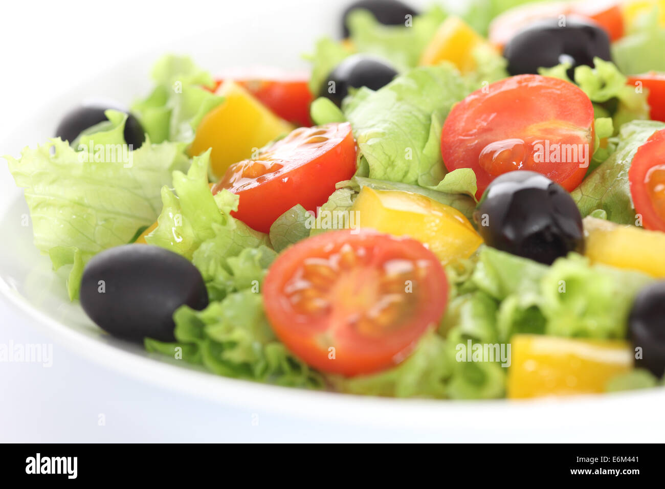 Vegan salad. Ingredients: lettuce, red cherry tomatoes, yellow bell pepper, black olives, olive oil. Stock Photo